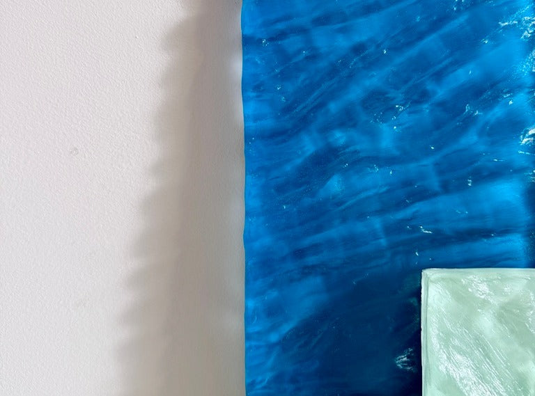 Blue poured resin piece leaning on a white wall